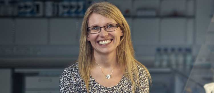 Profile of a lady with blonde hair and glasses, smiling