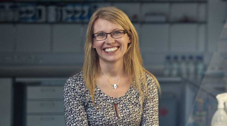 Profile of a lady with blonde hair and glasses, smiling